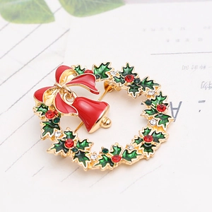 Macro view of Christmas wreath brooch with red bow, gold bells and sparkling rhinestones