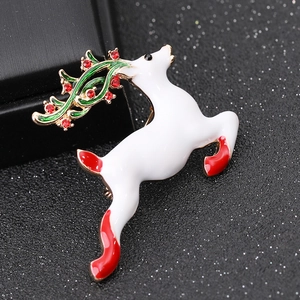 Macro view of a white enamel reindeer brooch with golden antlers and red rhinestones