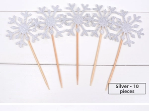 Détail de dix décorations de gâteau flocon de neige pailleté argenté sur bois blanc