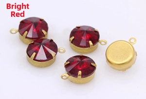 Close-up of deep red crystal glass jewelry components with gold prong settings and loops