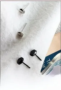 Close-up of geometric faceted silver and black minimalist earrings on white fabric