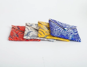 Macro detail of brocade jewelry pouches with traditional wave patterns and bead closures