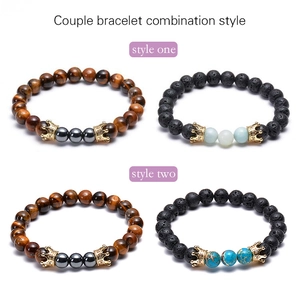 Detail shot of couple bracelets with tiger eye, lava stone, and golden crowns