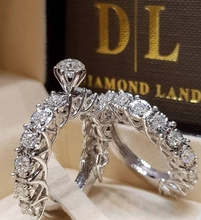 Macro shot of silver six-prong solitaire ring and eternity band in a dark brown jewelry box