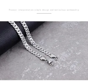 Détail du collier chaîne NK plate argentée avec fermoir mousqueton sur texture