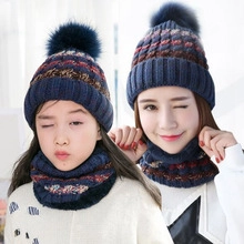 Detail of navy blue knitted beanie hat and neck warmer set with striped pattern and pom pom