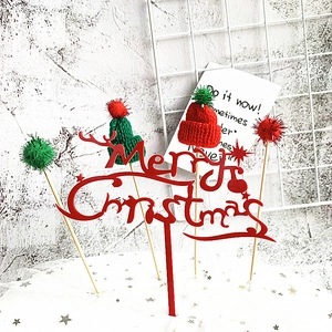 Macro detail of acrylic Merry Christmas cake topper with mini knit hats and pom-poms