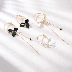 Détail de boucles d'oreilles pétales asymétriques avec chaînes dorées et perles