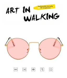 Detail of round gold metal frame sunglasses featuring pink high-definition lenses