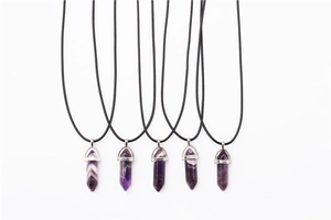 Macro detail of five hexagonal amethyst quartz point pendants with black cords on white backdrop