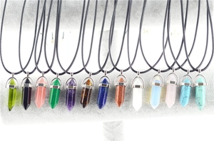 Various hexagonal crystal quartz point pendants displayed on a grey velvet jewelry stand