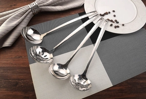 Macro detail of four stainless steel soup spoons and colanders on a checkered mat