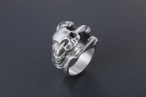 Macro shot of a silver punk skull ring on a dark grey background with metallic details