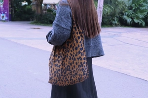 Detailed close-up of large leopard print canvas tote bag carried over the shoulder