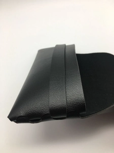 Detail view of the black textured leather surface and foldable closure on this sunglass case