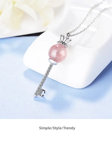 Detailed view of silver crown key pendant necklace with a pink strawberry crystal bead