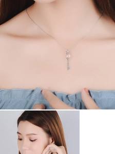 Macro detail of crown key pendant with pink stone and blue crystals on silver chain