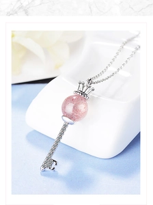 Macro shot of silver crown key necklace with pink crystal and zircon details