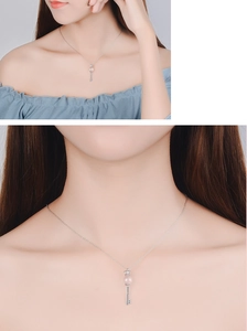 Detail of crown key pendant featuring a pink bead and blue micro-inlaid stones on silver chain
