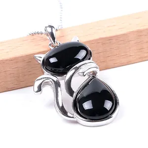 Cute black stone cat pendant necklace with silver chain on a wooden display stand