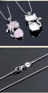 Close-up detail of silver cat pendant with pink crystal and white turquoise stone