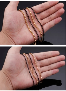 Detail showing gold and black stainless steel ball bead chains held by hand
