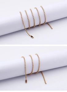 Detail of a shiny gold stainless steel ball bead chain wrapped around a white cylinder
