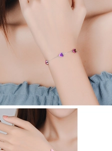 Detail of silver chain bracelet with three iridescent purple and pink heart pendants