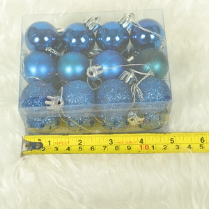 Detailed view of 12 blue Christmas ornaments in a box with a measuring tape for size