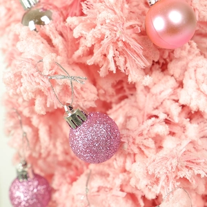 Macro detail of gradient pink Christmas balls with glitter and matte textures on tree