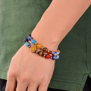 Solar system planets bracelet with natural agate beads on wrist with green fabric backdrop