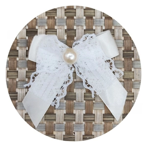 Detail of white lace bow accessory with satin ribbon and a central faux pearl bead