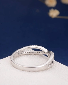 Macro detail of silver twisted crossover ring with micro-pave stones on blue background