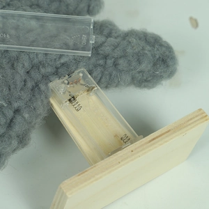 Lighted wool Christmas tree decoration with wooden base showing battery compartment detail