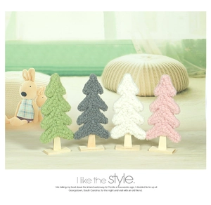Knitted wool Christmas trees in green, grey, white, and pink with wooden bases