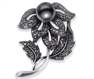 Detailed view of vintage flower brooch with black rhinestones and large black pearl