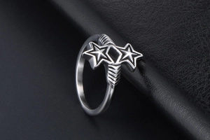 Detail view of silver double star ring with vintage texture on black leather background