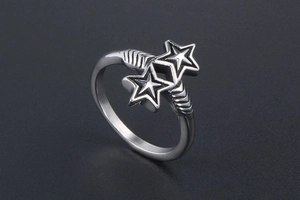 Macro detail of silver star ring featuring twin stars and textured band on black surface
