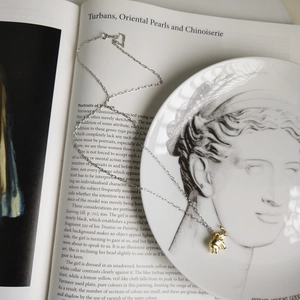 Detailed view of 925 silver elephant pendant on a decorative ceramic plate with art book