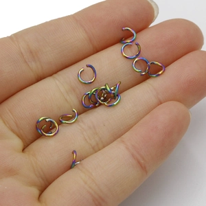 Rainbow plated stainless steel open jump rings held in hand for DIY jewelry making