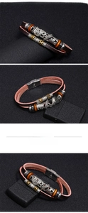 Macro shot of multi-layer leather bracelet featuring embossed dragon motif and steel clasp