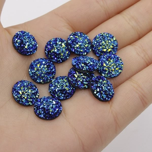 Close-up of 12mm blue round resin starry flatback rhinestones held in a hand