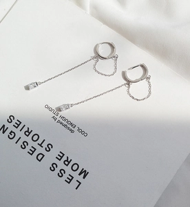 Detail view of silver tassel earrings with long chains and rectangular zircon pendants