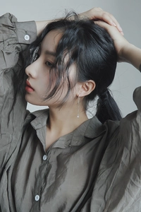 Close-up of silver long chain tassel earring with geometric pendant on model ear