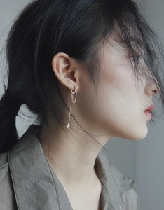 Detail view of silver drop chain earrings with cubic zirconia on a female model