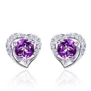 Macro shot of heart-shaped silver earrings with purple gemstones and white crystal borders