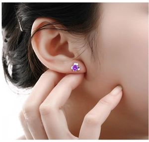 Detailed view of a purple flower stud earring with round-cut stone on a model ear