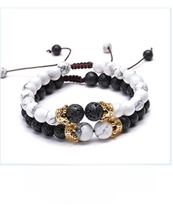 Macro detail of lava stone and turquoise beaded couple bracelets with gold crown charms