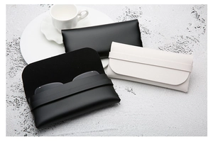 Detail of opening leather eyewear pouch showing soft black lining and textured PU finish