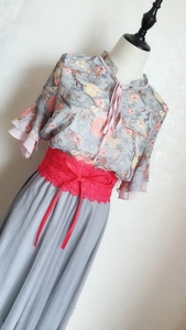 Detail eines roten breiten Korsettgürtels aus Spitze mit Chiffonbluse und Plissee-Rock